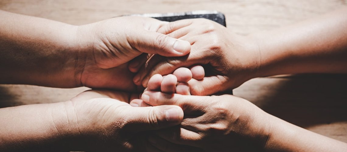 Couple of husband and wife are holding hands and pray together on wooden table with copy space for your text